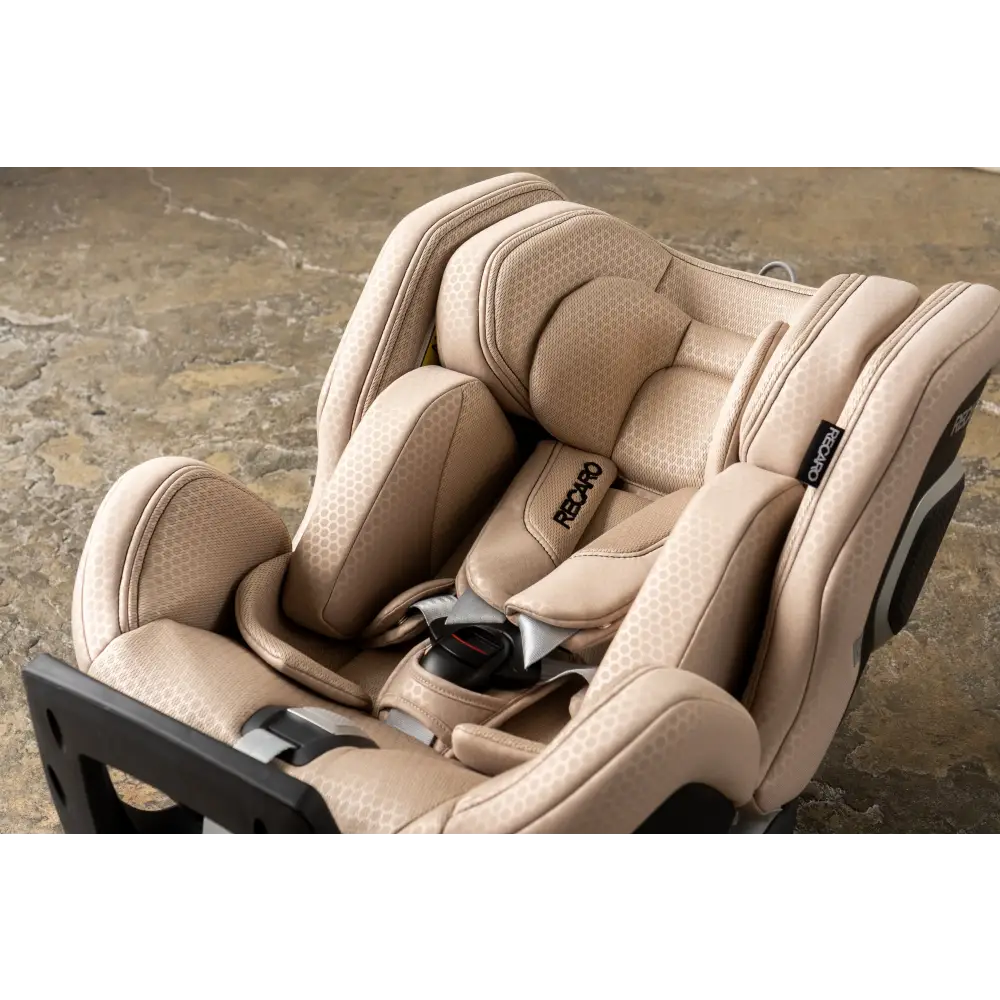 Close-up from above of the Elegant Beige XENON 1’s padded headrest, insert, shoulder harness and buckle.