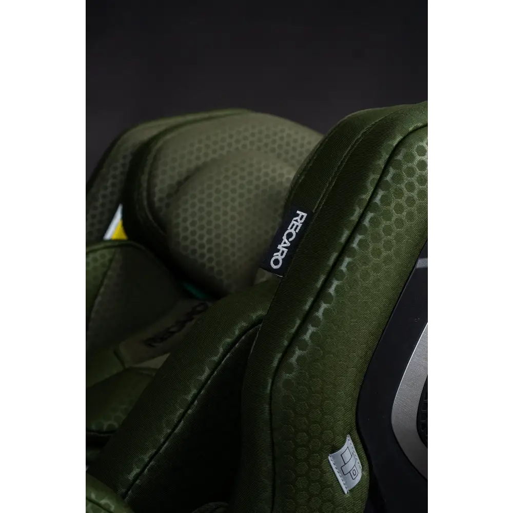Close-up of the Epic Green XENON 1’s stitched side wing, black Recaro label and grey seat belt symbol label.