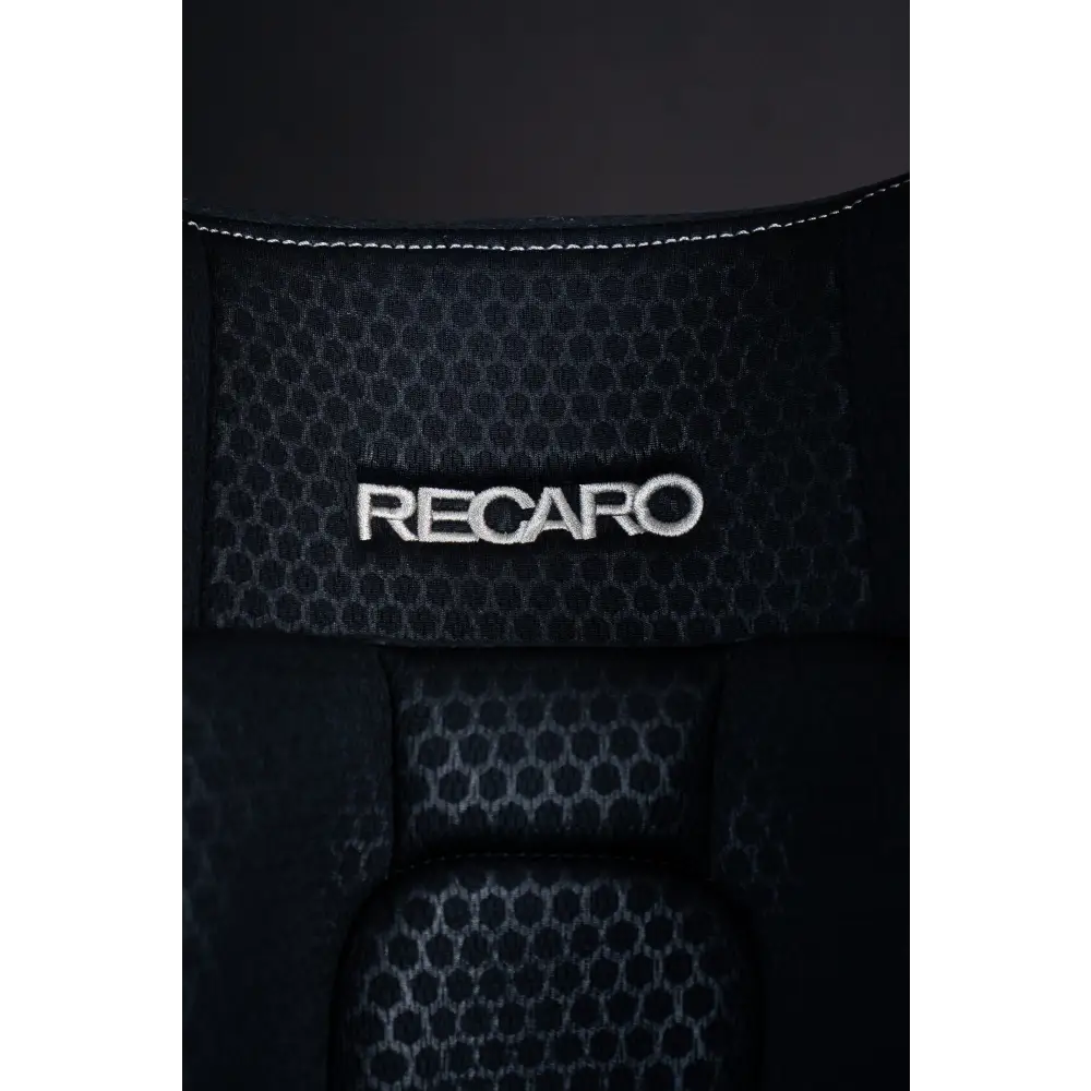Close-up of the white Recaro logo embroidered on Fresh Black honeycomb-patterned upholstery.