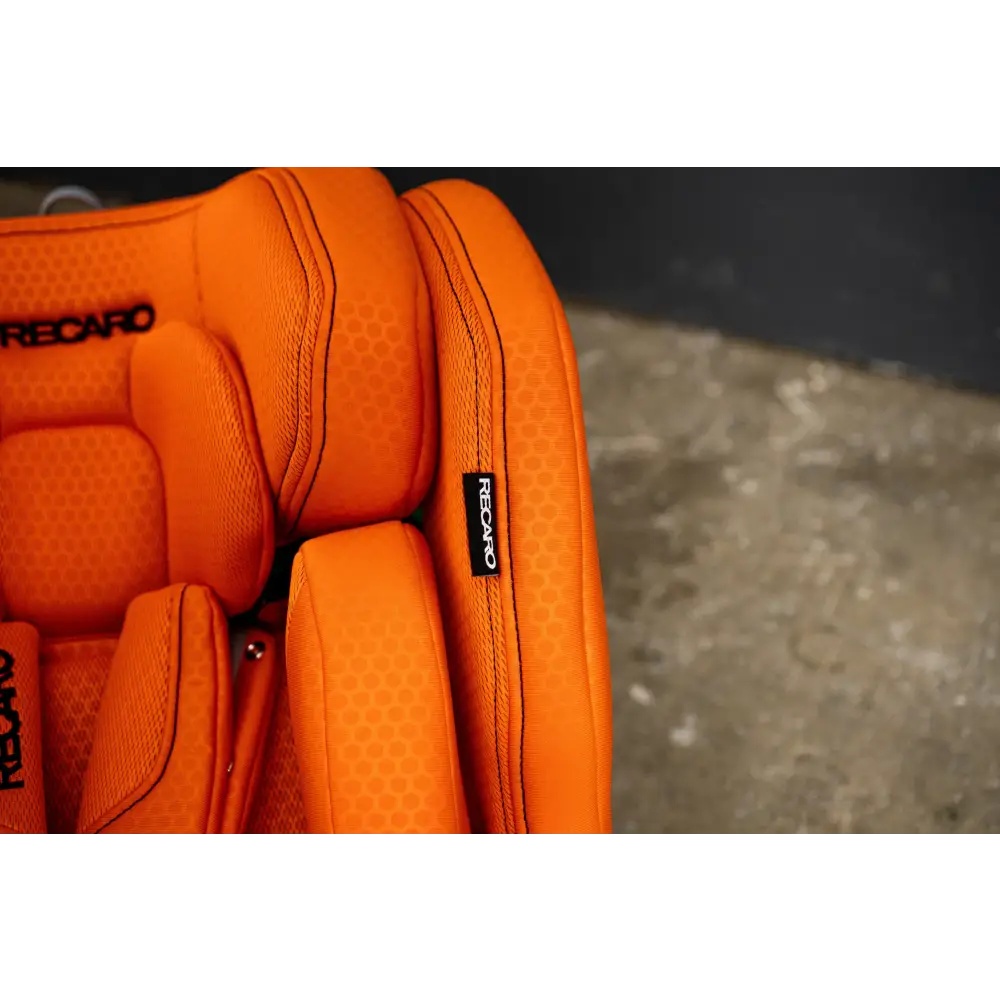 Close-up of the Vibrant Orange XENON 1’s padded headrest, stitched side wing and black Recaro fabric label.