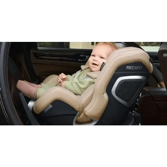 Child seated in an Elegant Beige Recaro XENON on a vehicle’s rear seat.