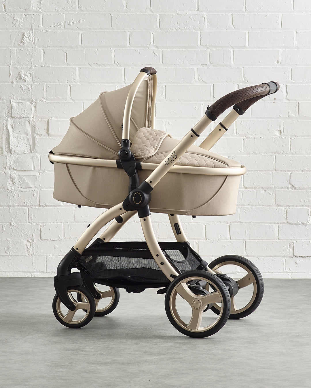 Beige egg baby stroller with quilted fabric and metallic frame.