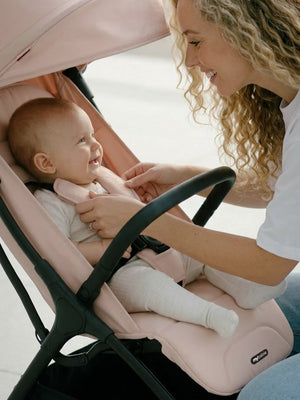 My Babiie MBX2 compact stroller in blush pink with black frame and adjustable canopy shown from the back side