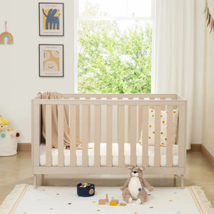 Beige wooden babymore dante crib with vertical slats white mattress and beige knitted blanket in cashmere nursery set