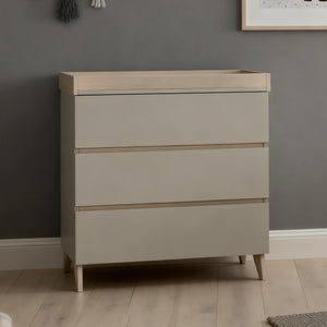 Beige three-drawer changing table with light wood accents and tapered legs from babymore dante nursery set