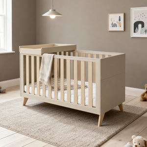 Babymore Dante cot bed in cashmere beige wood with slatted sides angled legs and cot top changer accessory