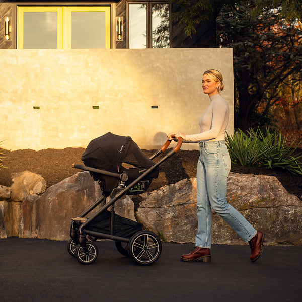 Black nuna pipa next infant carrier with wooden handle and silver-accented wheels in caviar color