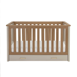 Babymore mira cot bed in cashmere warm oak with light oak slats cream sides and built-in storage drawer at base