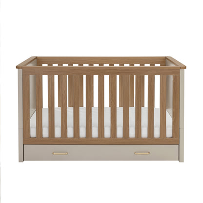 Babymore mira cot bed in cashmere warm oak with light oak slats cream sides and built-in storage drawer at base