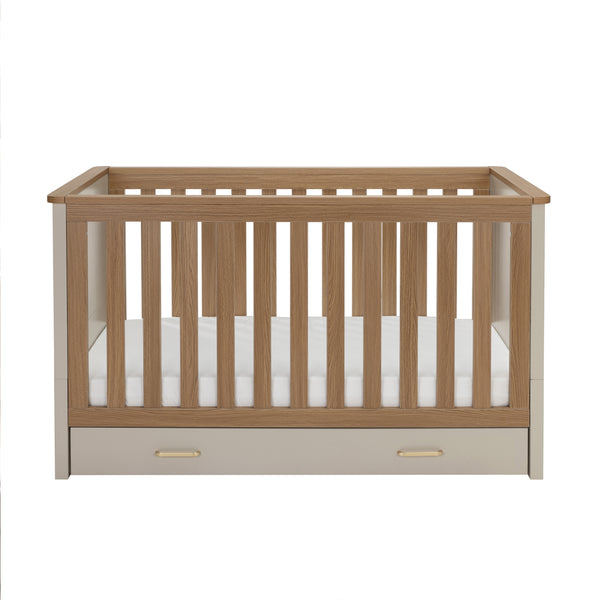 Babymore mira cot bed in cashmere warm oak with light oak slats cream sides and built-in storage drawer at base