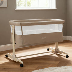 Beige babymore neera bedside crib with mesh sides and black caster wheels for easy mobility and ventilation