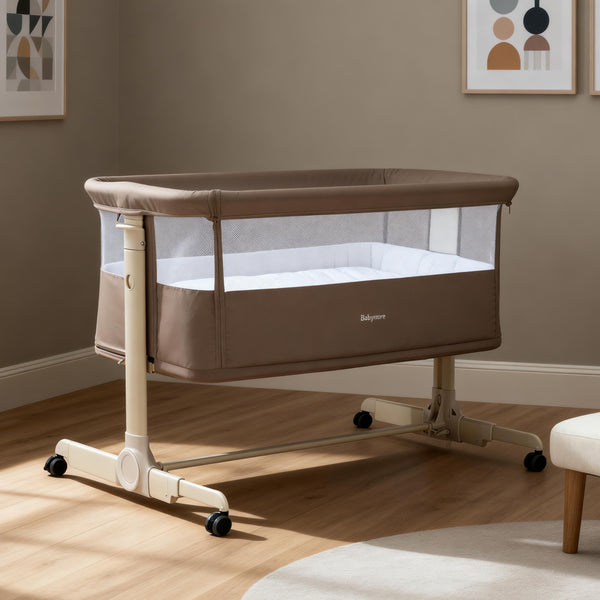 Beige babymore neera bedside crib with mesh sides and wheeled base for easy mobility in mocha color