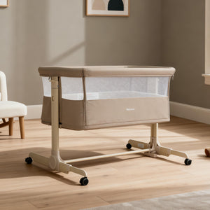 Beige babymore neera bedside convertible crib with mesh sides and caster wheels for easy mobility