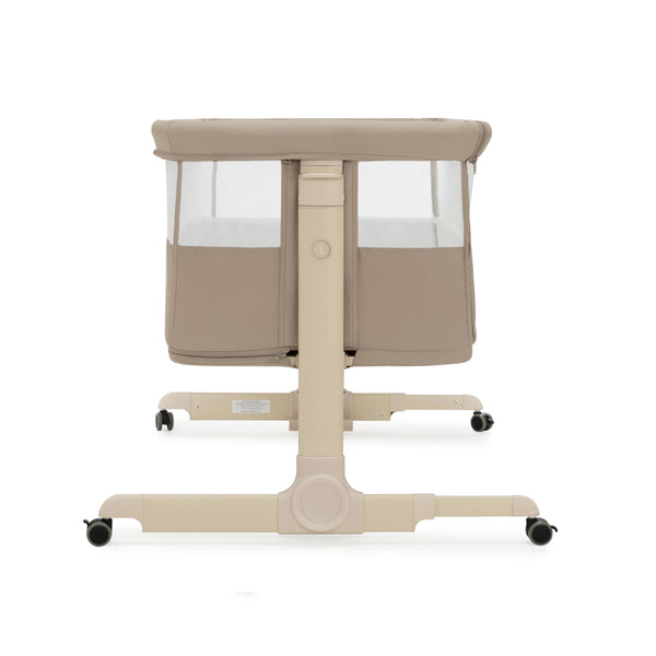 Beige babymore neera bedside convertible crib with mesh sides and black caster wheels in khaki color