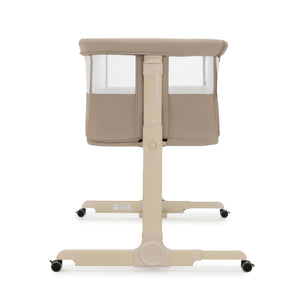 Beige Babymore Neera bedside convertible baby crib with mesh sides and black caster wheels in khaki color