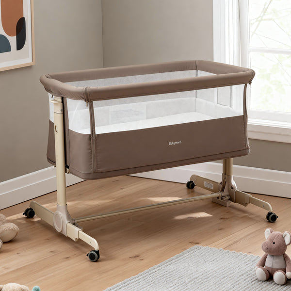 Beige babymore Neera bedside crib with mesh sides and wheeled base for easy mobility in mocha finish