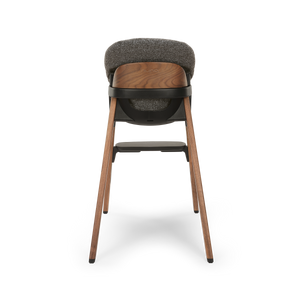 A modern wooden nuna bryn highchair with textured gray fabric seat and backrest black plastic base in sanderson