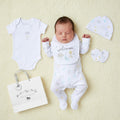 White baby onesie with subtle pastel cloud and star print from unisex welcome 5 piece layette set