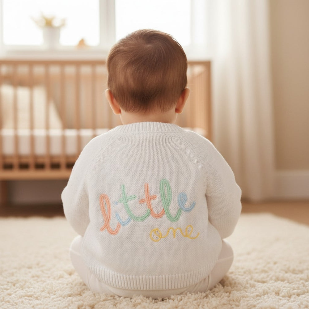 White knit unisex baby cardigan with colorful embroidered little one text on the back