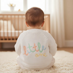 White knit unisex baby cardigan with colorful embroidered little one text on the back