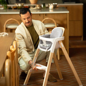 Nuna BRYN highchair heritage with white and light wood frame and gray upholstered seat and backrest for babies