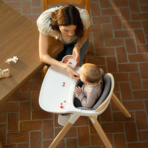 Nuna BRYN highchair in white and light wood with a gray cushioned seat for comfortable infant seating