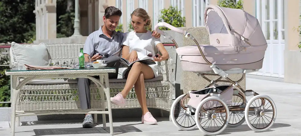 A delicate blush pink pram with a curved canopy and chrome-finished wheels.