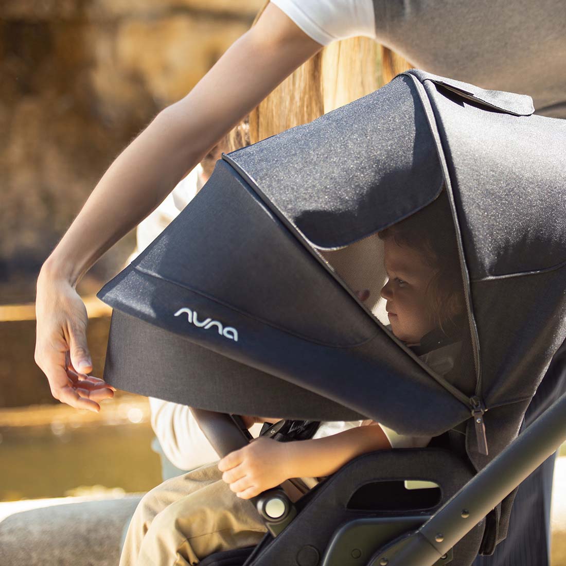 Dark gray fabric canopy with textured weave and white nuna logo on the side of nuna mixx next stroller caviar model
