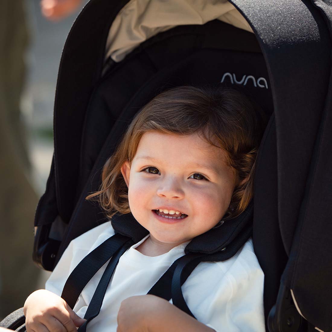 Black nuna mixx next stroller caviar with beige interior lining and smiling child seated inside