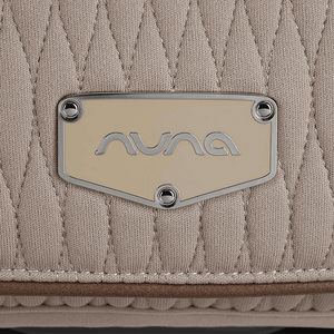 Beige quilted nuna brand patch with silver logo and rivets on nuna arra flex car seat cosmopolitan i size baby seat