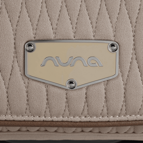 Beige quilted nuna brand patch with silver logo and rivets on nuna arra flex car seat cosmopolitan i size baby seat