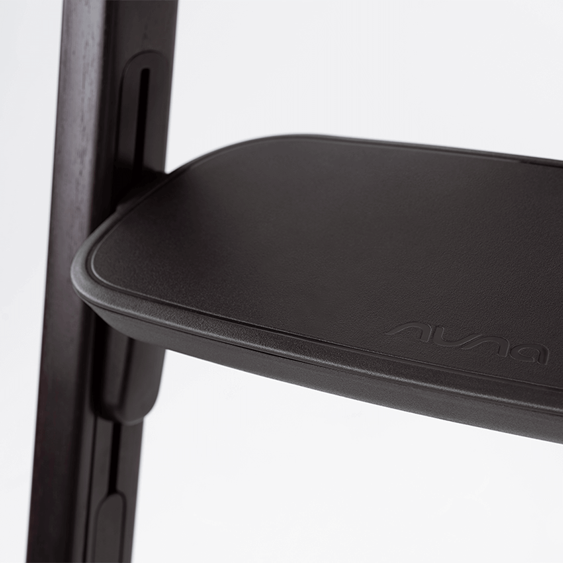 Black leather seat with embossed nuna logo on modern wooden frame of nuna bryn highchair metro back view
