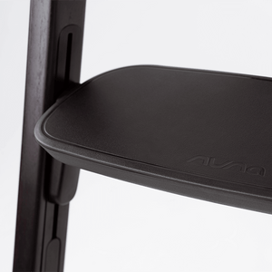 Black leather seat with embossed nuna logo on modern wooden frame of nuna bryn highchair metro back view