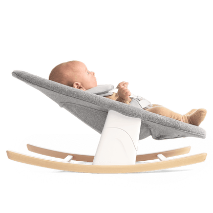 Nuna BRYN newborn rocker in gray fabric with white support and light wood rocking base for soothing babies