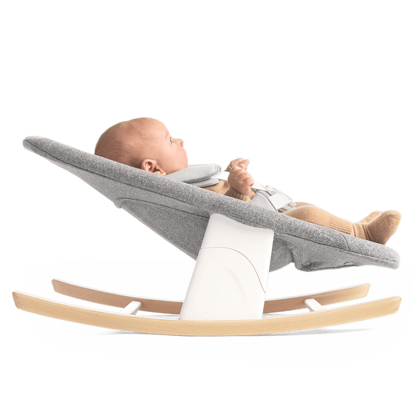 Nuna BRYN newborn rocker in gray fabric with white support and light wood rocking base for soothing babies