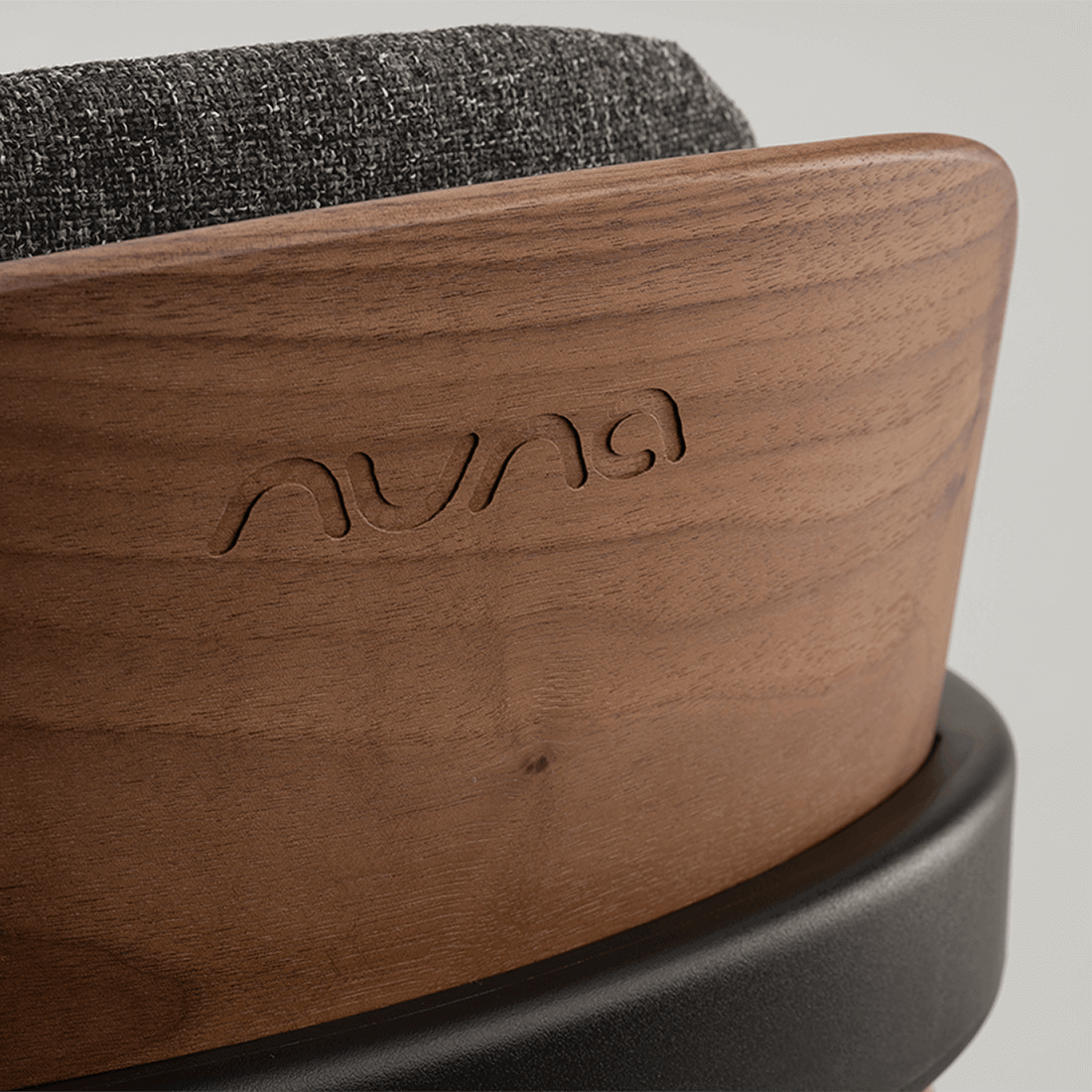 A sleek walnut wood nuna bryn highchair base with dark gray textured fabric top for stylish baby seating