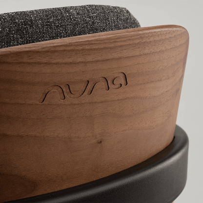A sleek walnut wood nuna bryn highchair base with dark gray textured fabric top for stylish baby seating