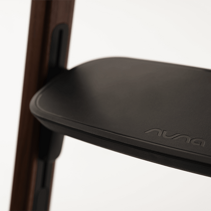 Nuna BRYN highchair sanderson with black matte plastic seat featuring auna branding and dark wood frame