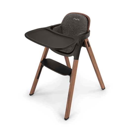 Modern nuna bryn highchair with wooden legs dark gray textured fabric seat and black plastic tray with brand logo