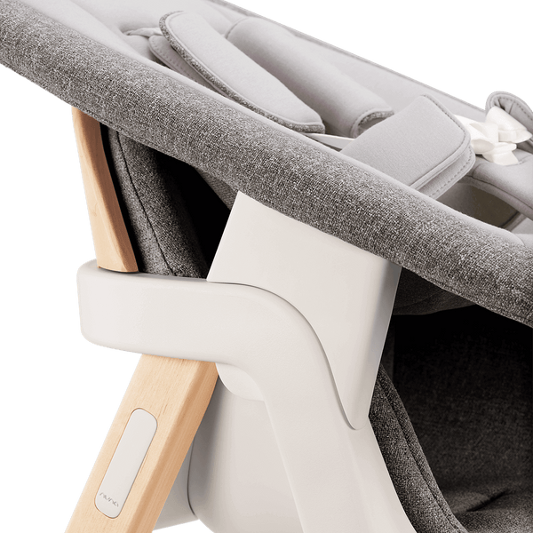 Nuna BRYN newborn rocker in gray textured fabric with light wood frame and white plastic accents for infant comfort