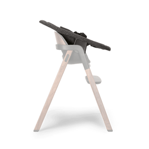 Modern high chair with dark gray textured fabric seat supported by wooden legs and black plastic joints Nuna BRYN newborn rocker