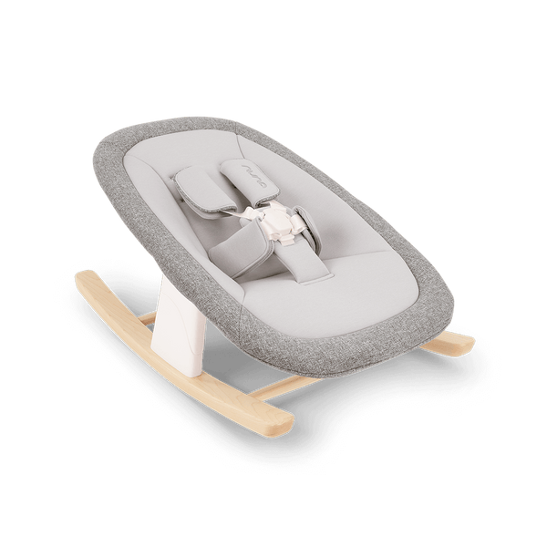 Gray textured fabric baby rocker with light wood base and white plastic support nuna bryn newborn rocker heritage