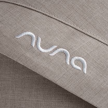 Beige textured fabric with white embroidered nuna logo on nuna mixx next stroller chateau seat upholstery