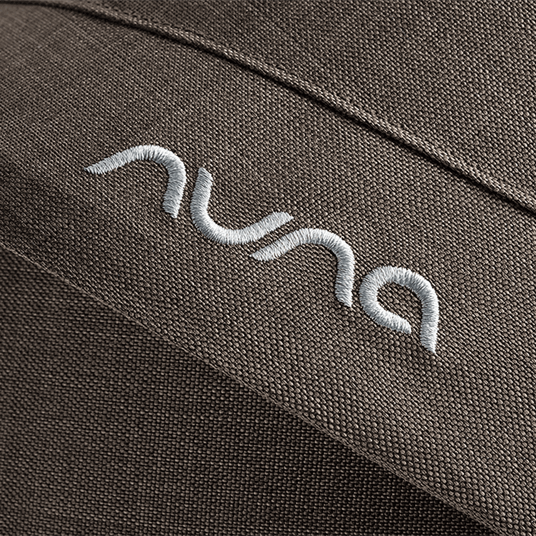 Close-up of embroidered nuna logo in white thread on dark brown fabric of nuna mixx next stroller chestnut