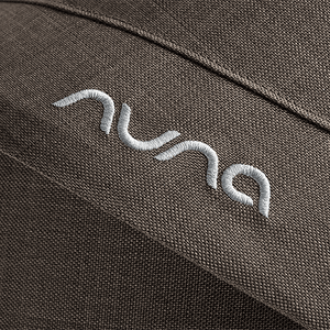 Close-up of embroidered nuna logo in white thread on dark brown fabric of nuna mixx next stroller chestnut