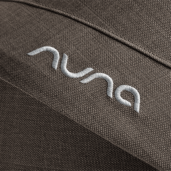 Close-up of embroidered nuna logo in white thread on dark brown fabric of nuna mixx next stroller chestnut
