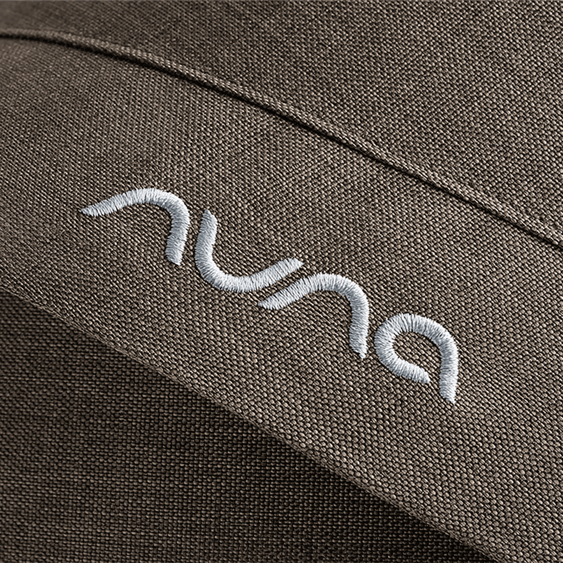 White embroidered nuna logo on textured olive green fabric of nuna mixx next stroller pistachio seat