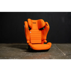 Recaro AXION 1 in Vibrant Orange, front view on a concrete floor against a dark background.