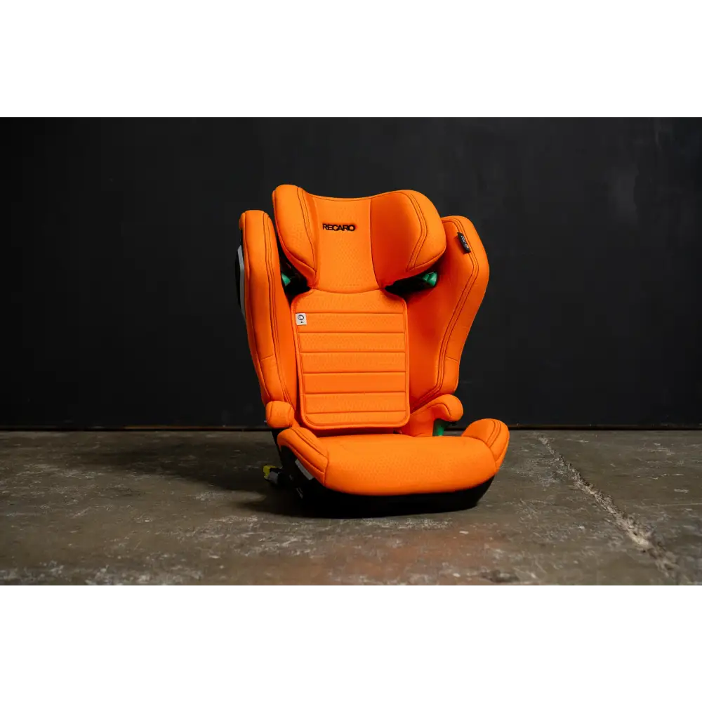 Recaro AXION 1 in Vibrant Orange, front view on a concrete floor against a dark background.