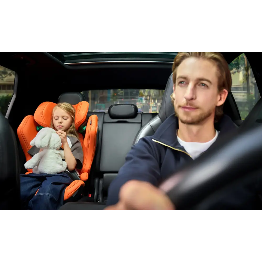 Child holding a soft toy in a Vibrant Orange AXION 1 on the rear seat, with an adult at the wheel.